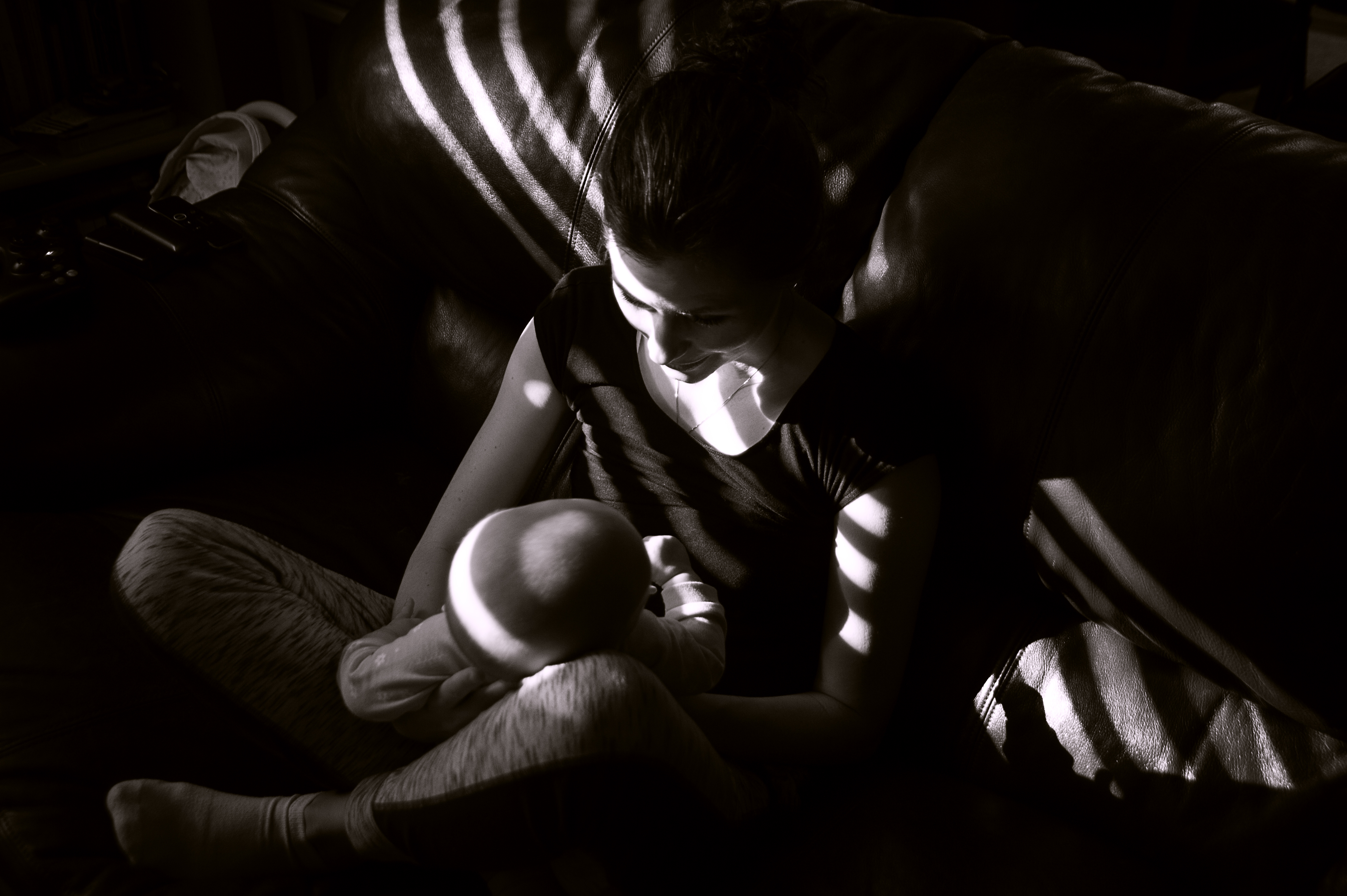 sun cuts through blinds creating shadow play on Diana and Brooklyn as they sit on the couch